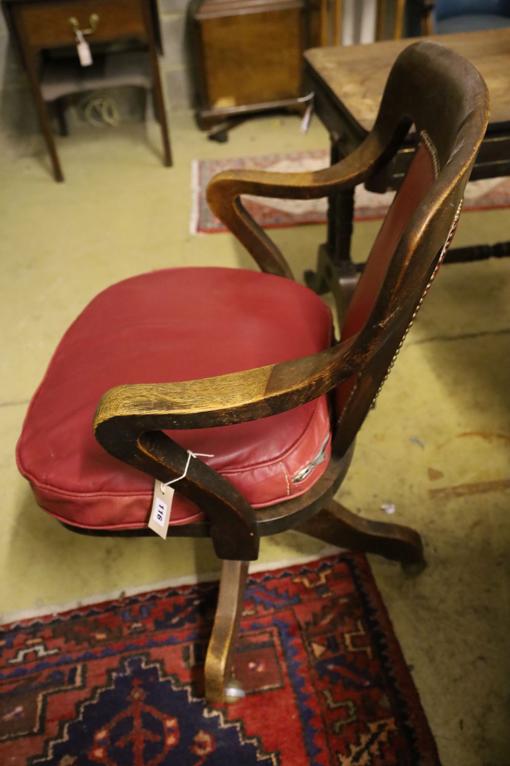 A 1920s oak swivel desk chair, the back and seat cushion covered in red hide, width 63cm, depth 50cm, height 94cm